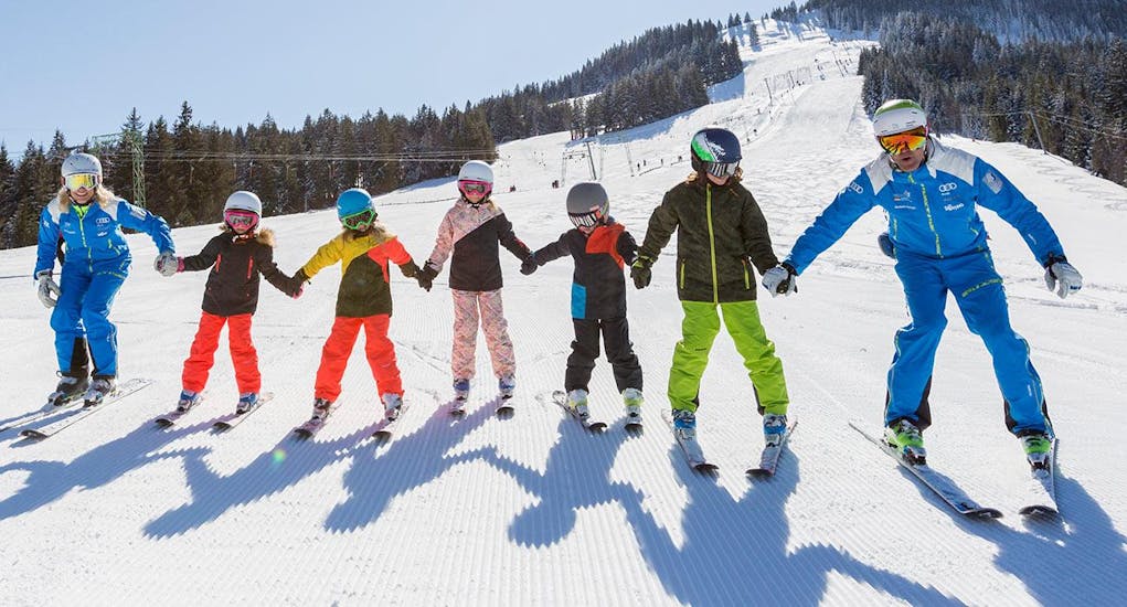 Eine Gruppe Kinder hat bei ihrem Kinder-Skikurs für Anfänger mit der Schneesportschule Balderschwang Spaß im Schnee. 