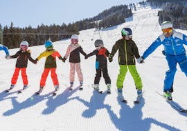 A group of children have fun in the snow during their kids ski lessons for first timers with the Schneesportschule Balderschwang.