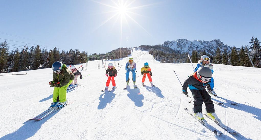 Een groep jonge skiërs racet de piste af tijdens hun kinderskilessen voor gevorderden bij de Schneesportschule Balderschwang.