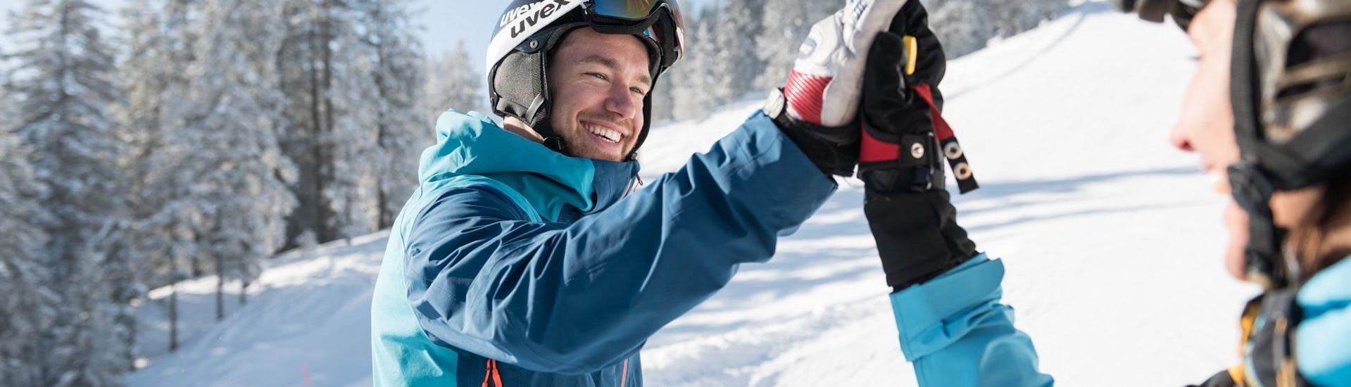 Ein Skifahrer und Skifahrer geben sich während dem privaten Skikurs für Erwachsene für alle Levels mit der Schneesportschule Balderschwang ein High-Five. 