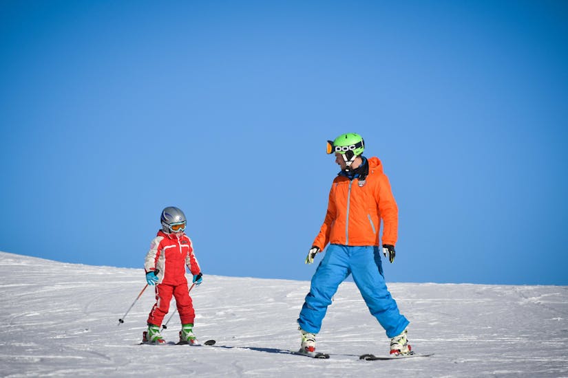 A young skier is skiing next to his instructor from the ski school YES Academy Sestriere during on of his Private Ski Lessons for Kids - All Levels.