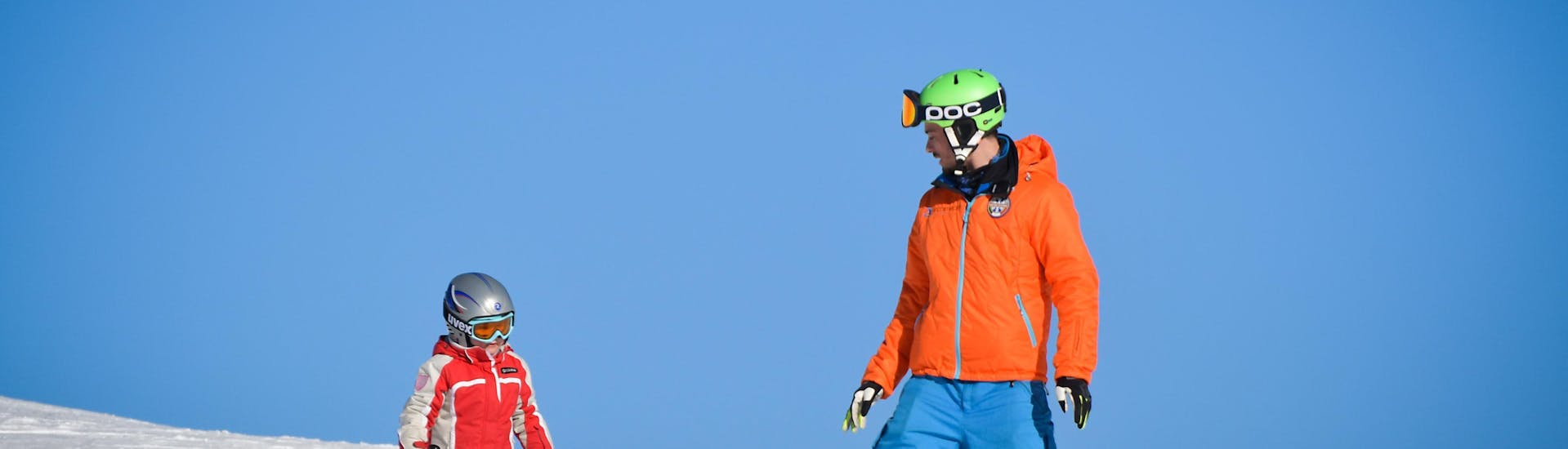 Un jeune skieur skie à côté de son moniteur de l'école de ski YES Academy Sestrières pendant un Cours particulier de ski pour Enfants.