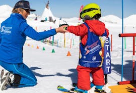 An instructor helps a small child as it takes it first steps on skis during Kids Ski Lessons (3-14 y.) for All Levels - Halfday with Schneesportschule Wildkogel.