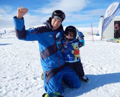 Ein Kind und ein Skilehrer machen ein gemeinsames Foto am Ende des ganztägigen Kinder-Skikurses (3-14 J.) für alle Levels mit der Schneesportschule Wildkogel.