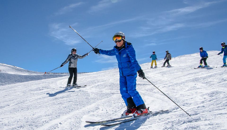 Een skileraar laat de groep zien hoe je bochten maakt en hoe je balanceert op ski's tijdens de volwassenenskilessen voor beginners bij Schneesportschule Wildkogel.