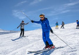 Een skileraar laat de groep zien hoe je bochten maakt en hoe je balanceert op ski's tijdens de volwassenenskilessen voor beginners bij Schneesportschule Wildkogel.