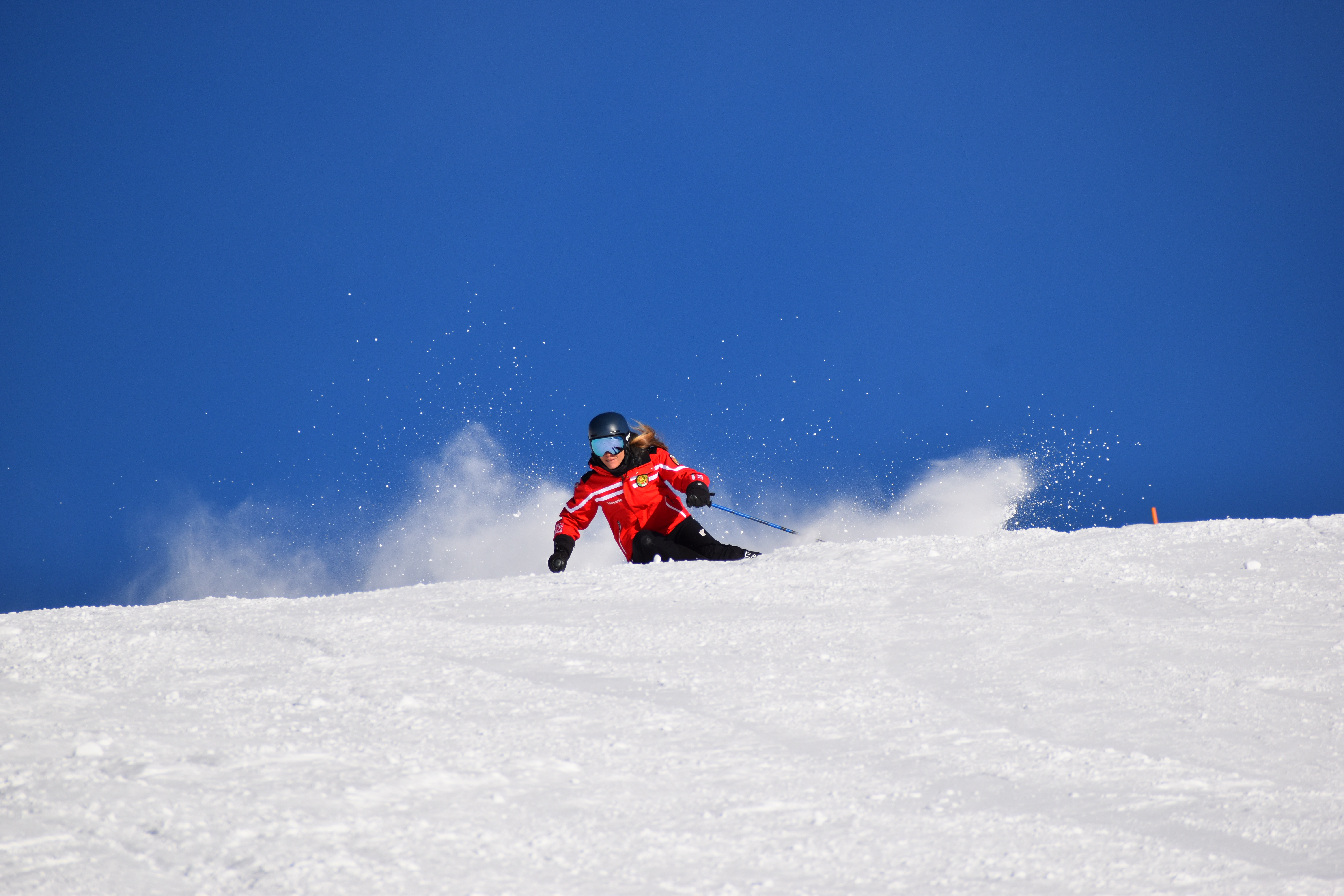 Begeisterte Skifahrer, die während ihres privaten Skikurses für Erwachsene aller Niveaus mit der Ride'em Ski School Breuil-Cervinia die Pisten hinunterfahren.
