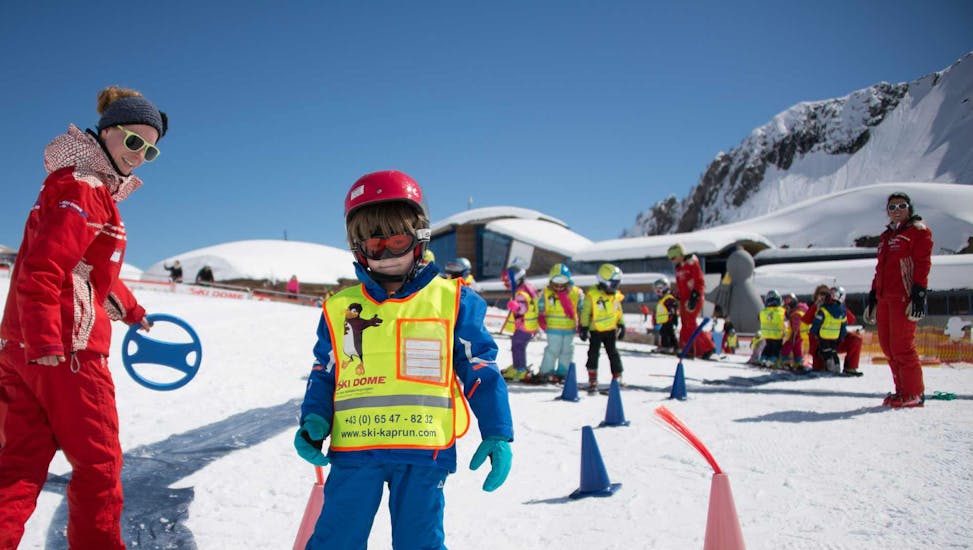 Een grote groep kinderen en instructeurs aan het oefenen tijdens de skilessen voor kinderen "BOBOs kids club" voor beginners bij skischool Ski Dome Viehhofen.