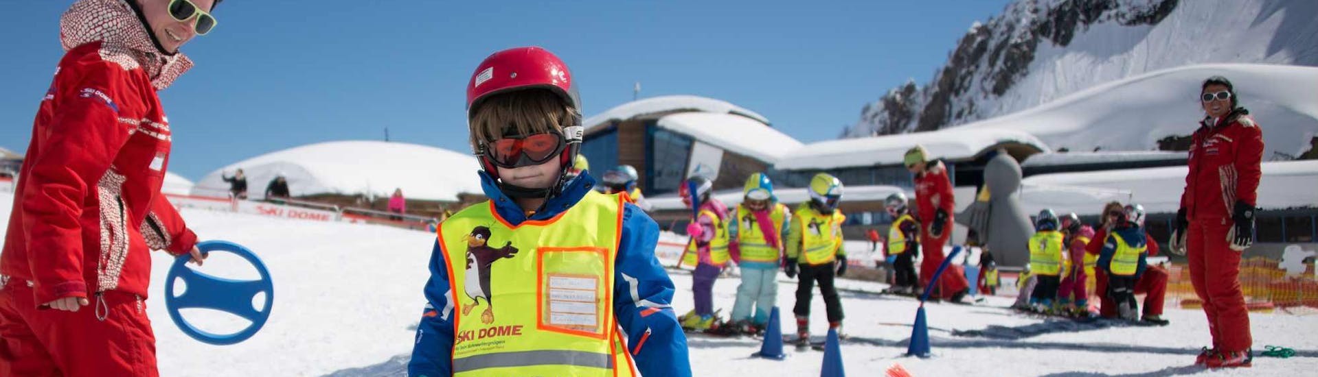 A large group of kids and instructors practising during kids ski lessons "BOBOs kids club" for beginners with ski school Ski Dome Viehhofen.