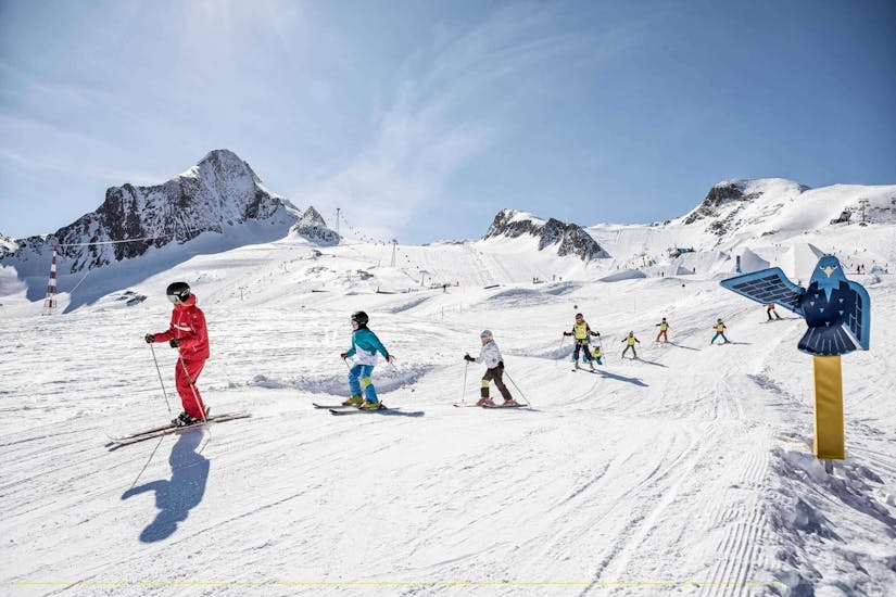 Een groep kinderen skiën de piste af tijdens hun Skilessen voor kinderen "BOBOs Kids Club" (4-15 j.) voor gevorderden met Ski Dome Viehhofen.
