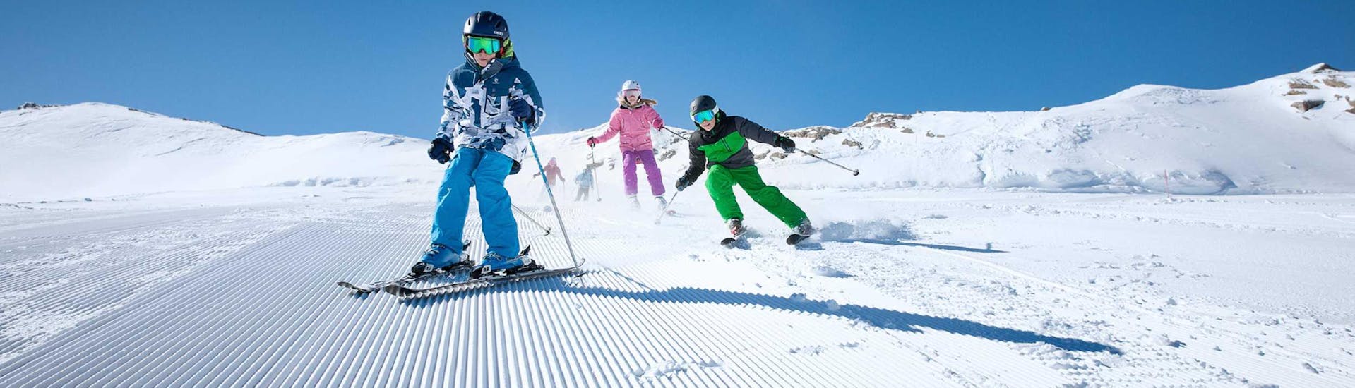 Drei Kinder rasen beim Kinderskikurs All-in-One für Fortgeschrittene mit dem Ski Dome Viehhofen die Pisten hinunter.