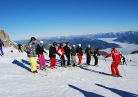 A large group of adults with their ski instructor during adult ski lessons for beginners with ski school Ski Dome Viehhofen.