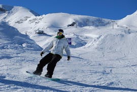 Ein Snowboarder auf der Piste während eines Snowboardkurses für Erwachsene für Anfänger mit der Skischule Ski Dome Viehhofen.