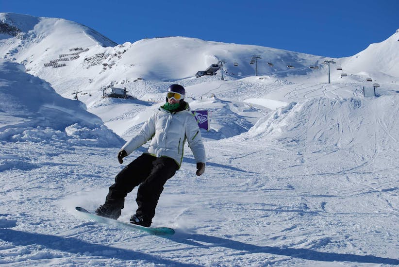 Een snowboarder op de piste tijdens de snowboardlessen voor volwassenen voor beginners bij skischool Ski Dome Viehhofen.