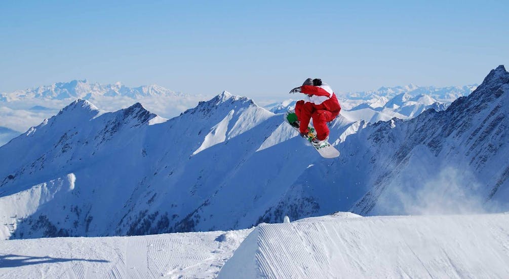 Een snowboarder vliegt door de lucht tijdens snowboardlessen voor volwassenen voor gevorderden bij skischool Ski Dome Viehhofen.