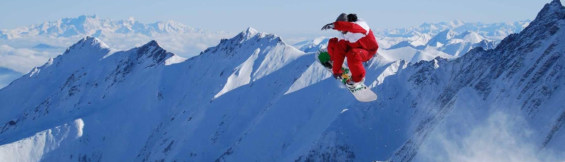 Ein Snowboarder fliegt durch die Luft beim Snowboardkurs für Erwachsene und Fortgeschrittene mit der Skischule Ski Dome Viehhofen.