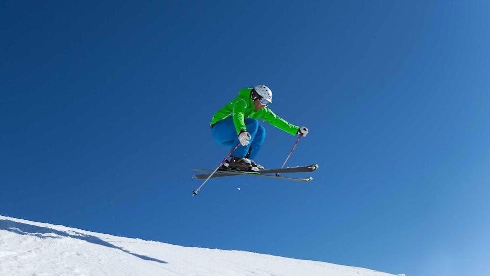 Een skiër vliegt door de lucht tijdens privé skilessen voor volwassenen van alle niveaus bij skischool Ski Dome Viehhofen.