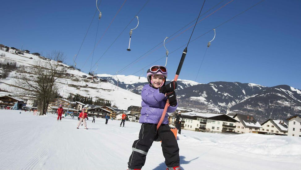 Ein Kind benutzt einen Lift während eines privaten Kinder-Skikurs aller Stufen mit der Skischule Ski Dome Viehhofen.