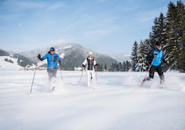 Three winter sports enthusiasts attend the private cross-country ckiing lessons for all levels - classic at the Balderschwang snow sports school. 