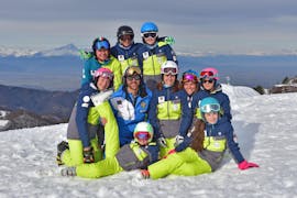 Kinderen poseren voor een foto met hun instructeur van de ski- en snowboardschool Scuola di Sci e Snowboard Prato Nevoso aan het einde van hun kinderskilessen (5-14 jaar) voor alle niveaus.