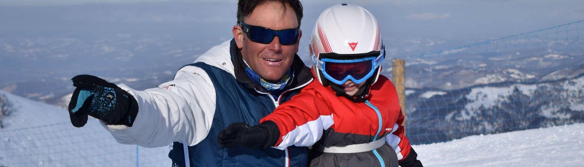 Ein junges Kind lernt gemeinsam mit seinem Snowboardlehrer von der Skischule Scuola di Sci e Snowboard Prato Nevoso im Rahmen der Angebots Snowboardkurs für Kinder (5-14 Jahre) - Alle Levels das Snowboarden.