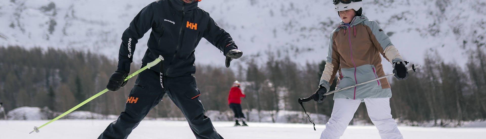 Moniteur aidant une jeune adulte pendant une leçon de ski privée pour adultes de tous niveaux à Chamonix.