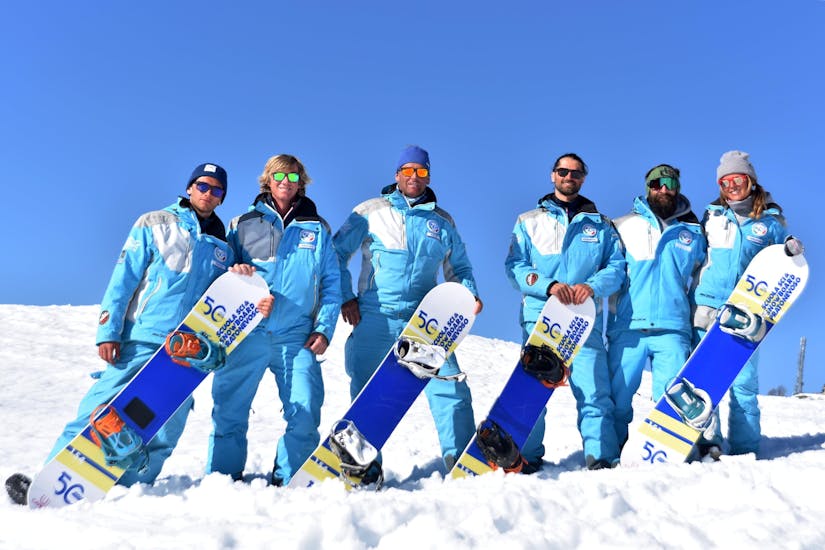 Snowboardinstructeurs glimlachen naar de camera in Prato Nevoso na een van de privé-snowboardlessen voor kinderen en volwassenen van alle niveaus.