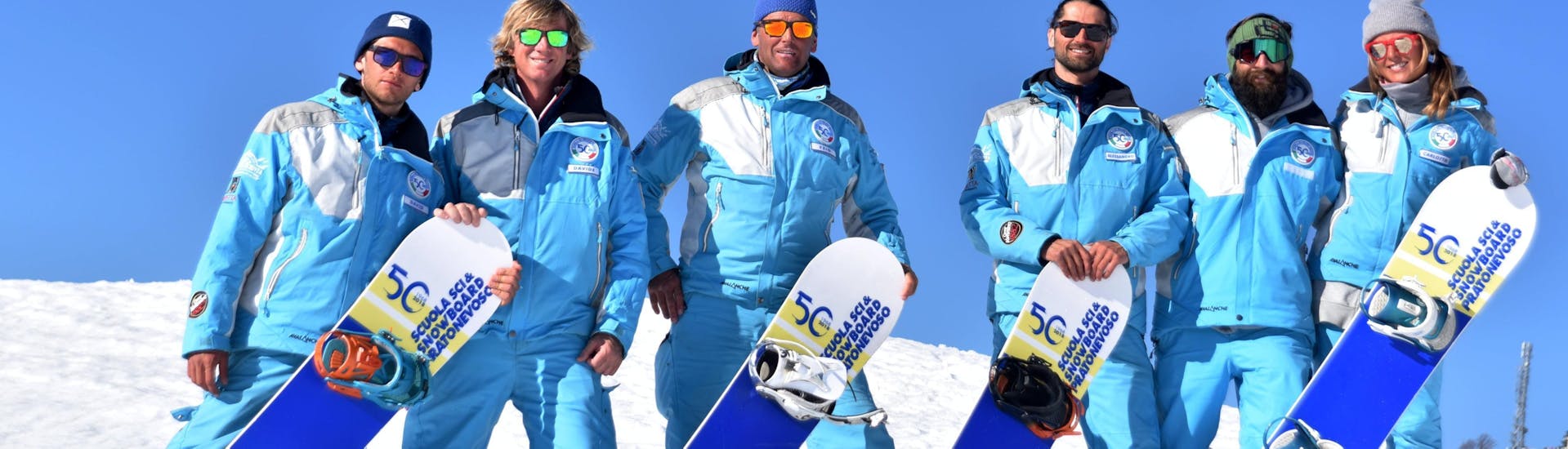 Snowboardinstructeurs glimlachen naar de camera in Prato Nevoso na een van de privé-snowboardlessen voor kinderen en volwassenen van alle niveaus.