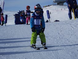 Een klein kind gebruikt de sneeuwploeg tijdens privé skilessen voor kinderen van alle leeftijden bij Schneesportschule Wildkogel.