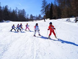 A grouf of kids is improving their skills on the slope during Kids Ski Lessons (5-15 years) - With Experience with the ski school Scuola di Sci e Snowboard Cristallo Cortina.