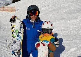 Een kind en zijn instructeur tijdens hun privé snowboardlessen voor alle niveaus hebben een geweldige tijd bij Schneesportschule Wildkogel.
