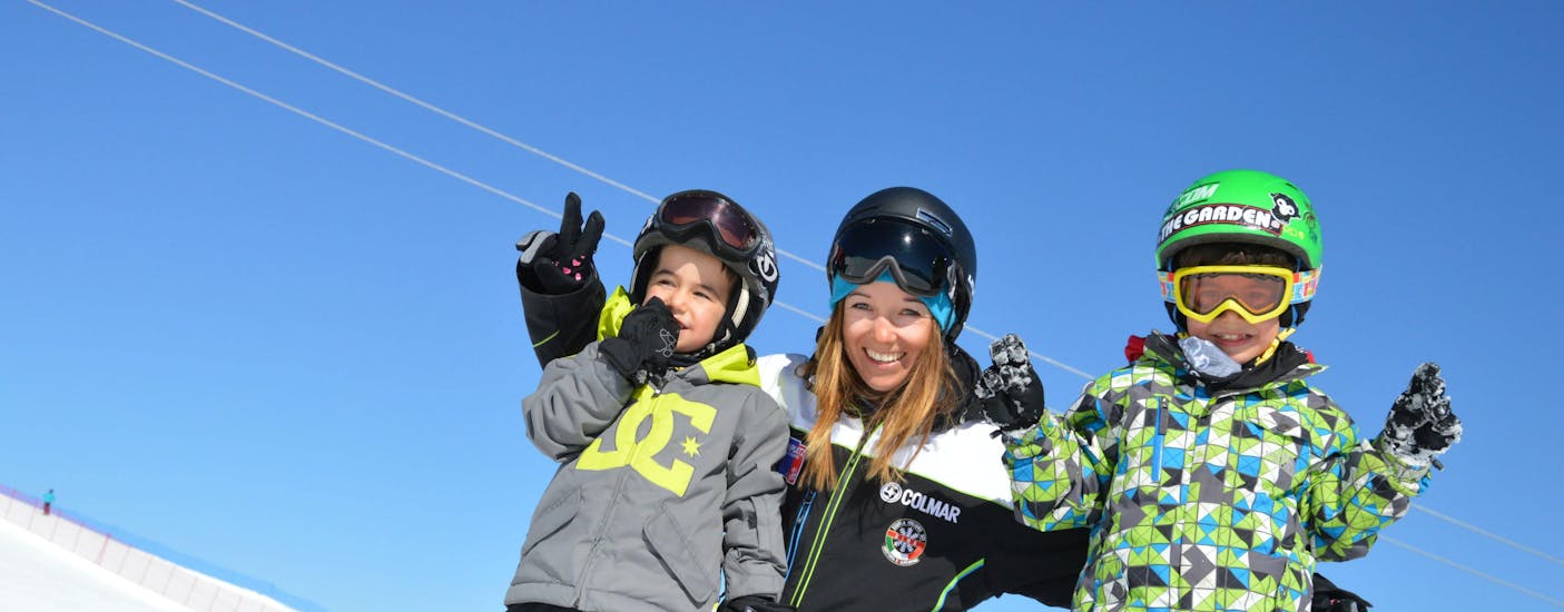 Deux enfants avec leur moniteur pendant les cours de snowboard pour enfants pour débutants avec Cimaschool Plan de Corones.