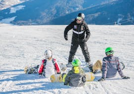 A group of kids listening to the instructor during the kids snowboarding lessons for beginners with Cimaschool Plan de Corones.