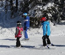 Maestro di sci con i bambini sulle piste del Monte Elmo durante una delle lezioni di sci per bambini alle prime armi.