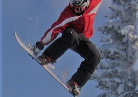 Een snowboarder laat een paar indrukwekkende trucs zien tijdens de snowboardlessen voor kinderen (8-14 jaar) voor Intermediate bij de skischool Skischule Lechner in Zell am Ziller.