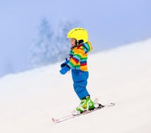 Ein Kind genießt sein erstes Mal auf dem Schnee in Monte Elmo während eines der privaten Skikurse für Kinder aller Stufen.