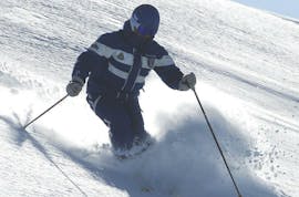 Un maestro di sci è in neve fresca, mostrando la tecnica giusta ai partecipanti delle lezioni private di sci fuori pista per sciatori con esperienza a Monte Elmo.