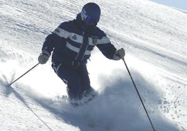 A ski instructor is in fresh snow, showing the right technique to the participants of the private off-piste skiing lessons for skiers with experience in Monte Elmo.