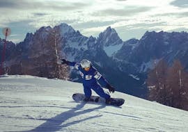 A snowboard instructor is training before one of the private snowboarding lessons for all levels in Monte Elmo.