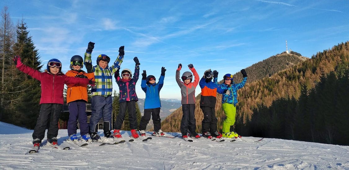 Eine Kindergruppe jubelt während dem Kinder-Skikurs (5-17 J.) für Skifahrer mit Erfahrung.