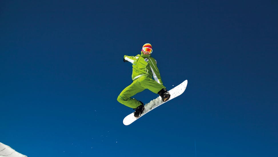 A snowboarder is jumping during snowboarding lessons for all levels with ski school Club Alpin in Grän.