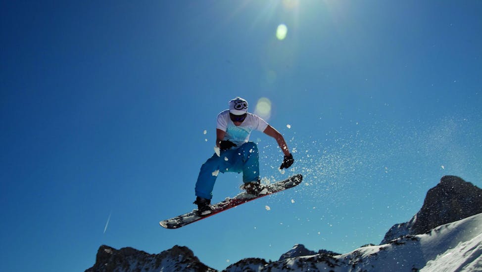 Een snowboarder springt tijdens privé snowboardlessen voor kinderen en volwassenen bij skischool Club Alpin in Grän.