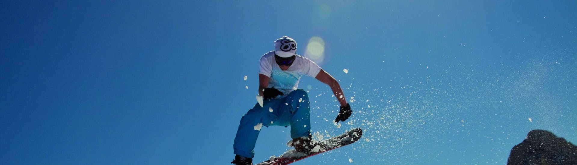 Ein Snowboarder springt beim privaten Snowboardunterricht für Kinder und Erwachsene mit der Skischule Club Alpin in Grän.