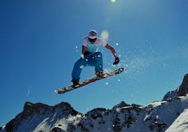 Een snowboarder springt tijdens privé snowboardlessen voor kinderen en volwassenen bij skischool Club Alpin in Grän.