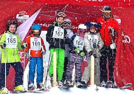 A group of children is getting ready for their final race after participating in Kids Ski Lessons (6-14 years) - Full Day - Advanced with the ski school Scuola Sci Cortina.