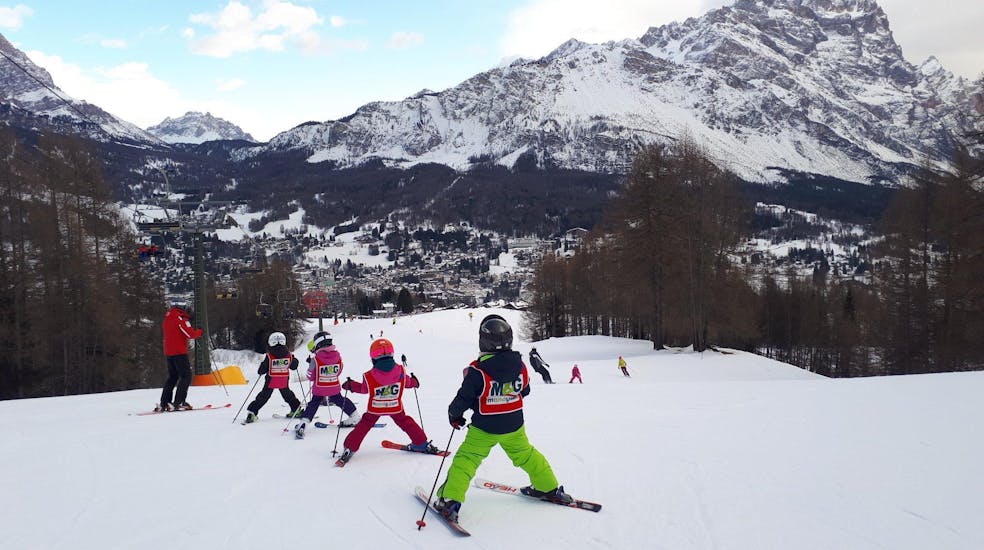 Des enfants suivent de près le moniteur de ski à Cortina pendant l'un des cours de ski pour enfants (4-10 ans) pour débutants.