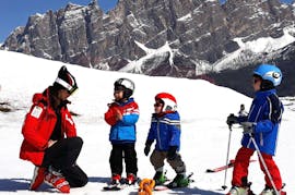 Twee jonge kinderen leren skiën met hun zorgzame instructeur van de skischool Scuola Sci Cortina tijdens Kinderskilessen (4-10 jaar) - Beginners.