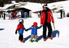Des frères et sœurs et leur moniteur de ski de l'école de ski Scuola Sci Cortina sur les pistes pendant les cours particuliers de ski pour enfants - tous niveaux.