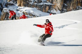 Il maestro di snowboard della Scuola Sci Cortina conduce un allievo lungo la pista durante Lezioni private di snowboard - Tutte le età e livelli.