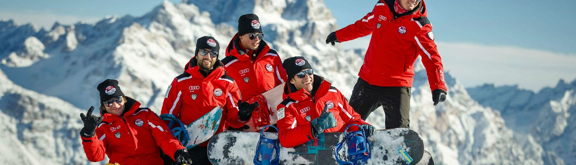 Een groep snowboardleraren van de skischool Scuola Sci Cortina vermaakt zich in de sneeuw tijdens een van hun privé-snowboardlessen voor kinderen en volwassenen - alle niveaus in het skigebied van Cortina d'Ampezzo.